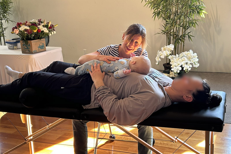 Chloe Sardin giving an osteopathic treatment to a mother and her child