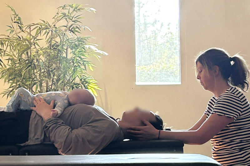Osteopathic therapist in Calgary treating a mom and child together on treatment table